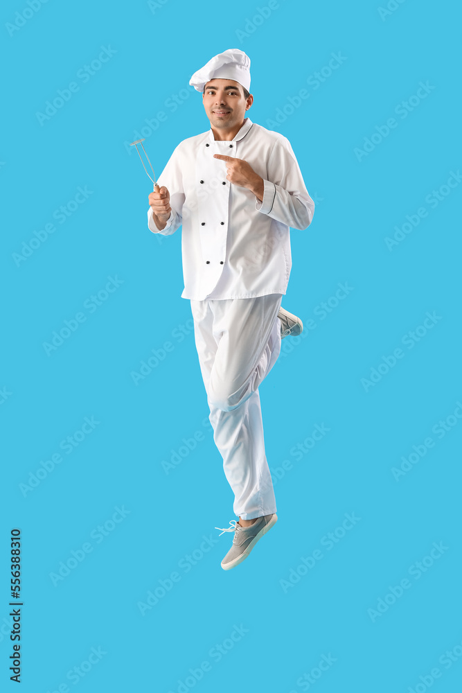 Young chef with masher jumping on blue background