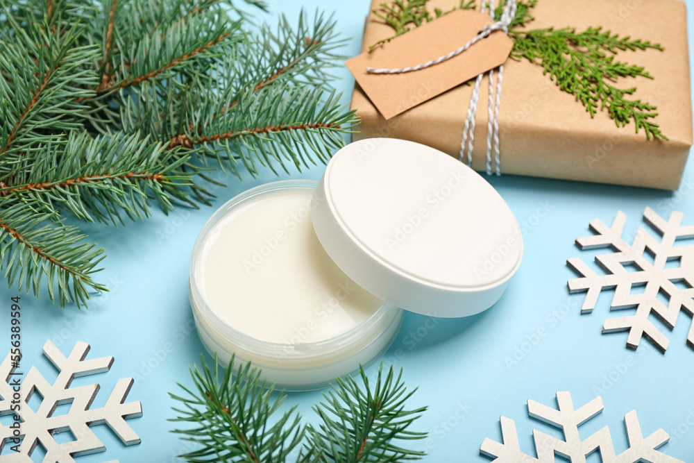 Jar of cream, fir branches and Christmas decorations on color background