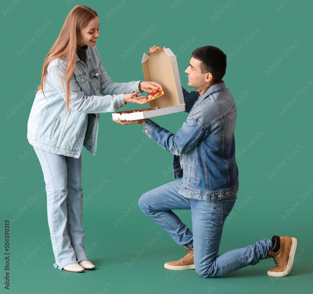 Happy young couple with fresh pizza on green background. Creative marriage proposal