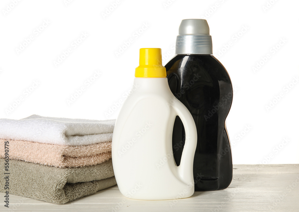 Laundry detergents and towels on table against white background