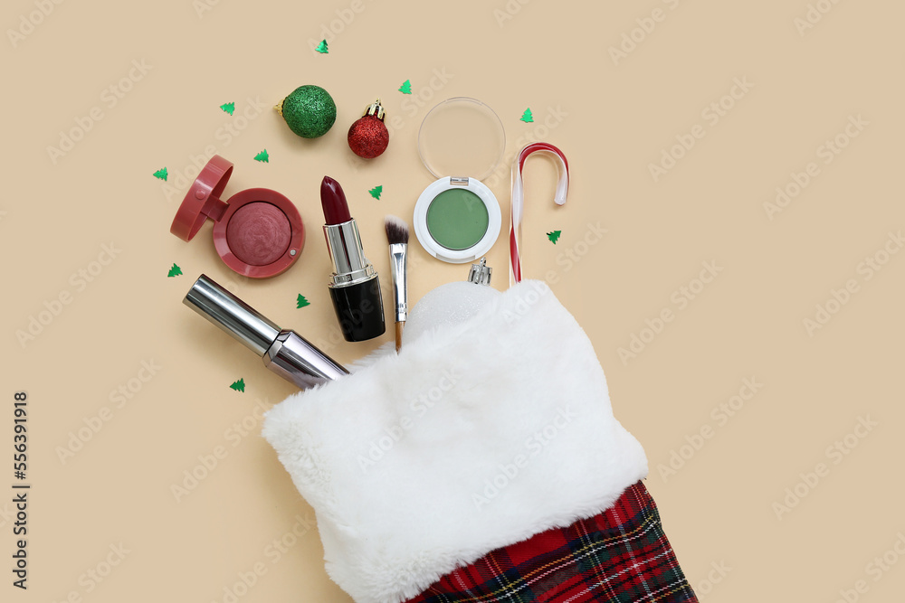 Christmas sock with cosmetics and decorations on color background