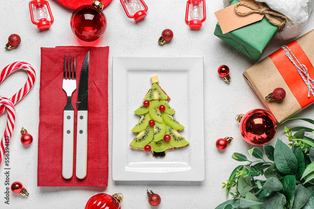 Composition with plate of tasty Christmas tree pancake, gifts and decorations on light background