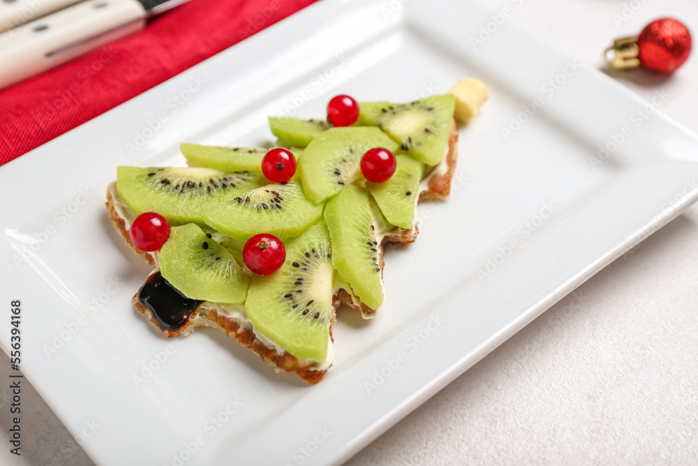 Plate with tasty Christmas tree pancake with fruits on light background, closeup