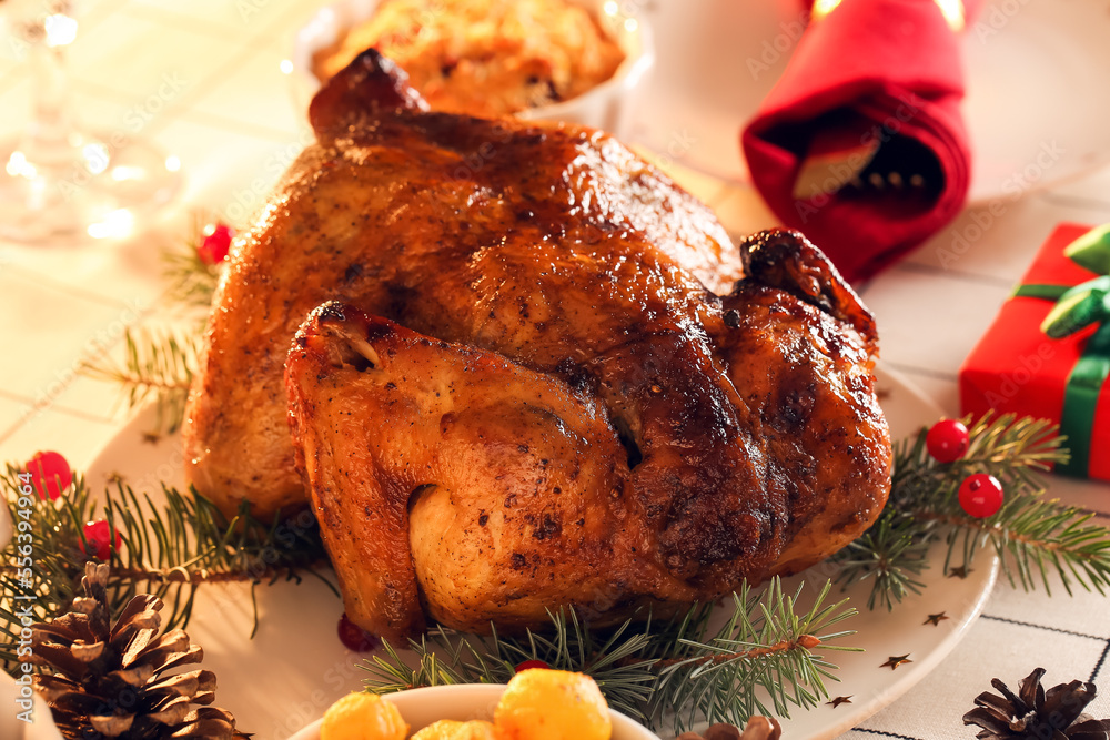 Plate with tasty chicken and Christmas branches on dining table in room, closeup