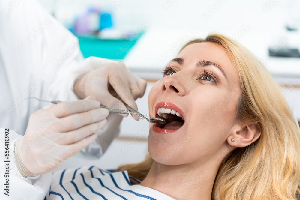 Female dentist examine tooth to Caucasian girl at dental health clinic. 