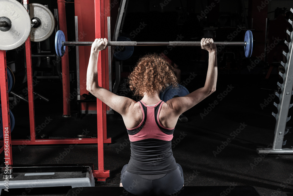 Woman bodybuilder engaged with a barbell in the gym