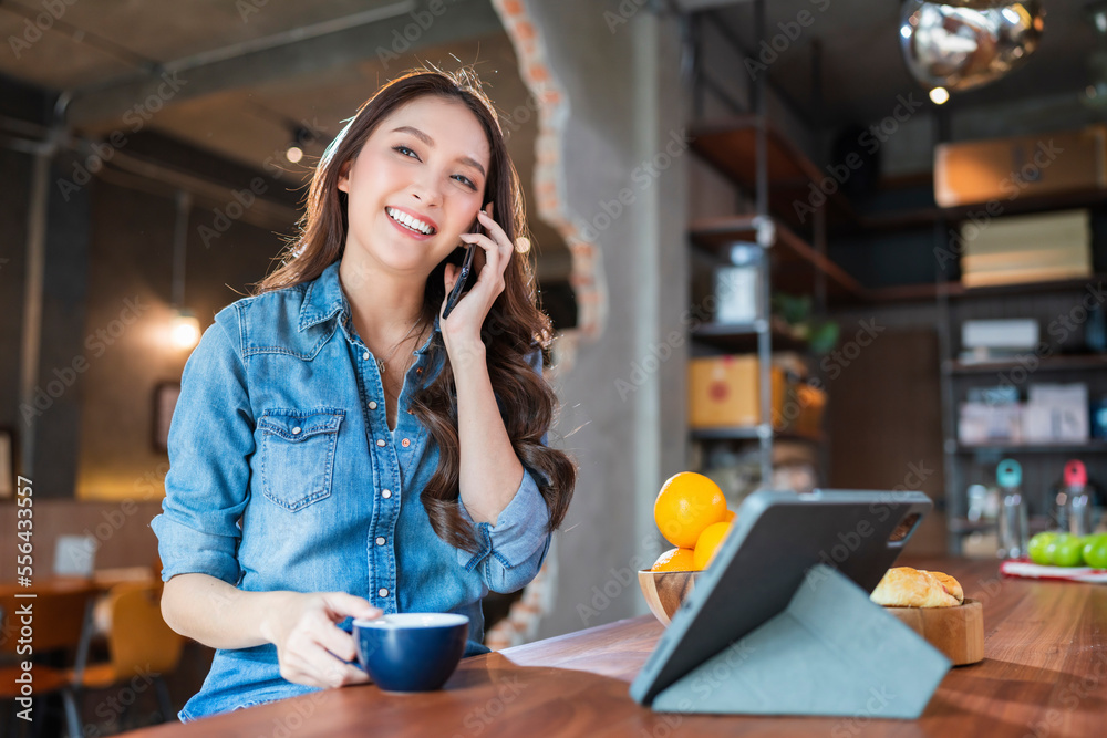 asian female cheerful woman hand using smartphone tablet working from kitchen at home while drink co