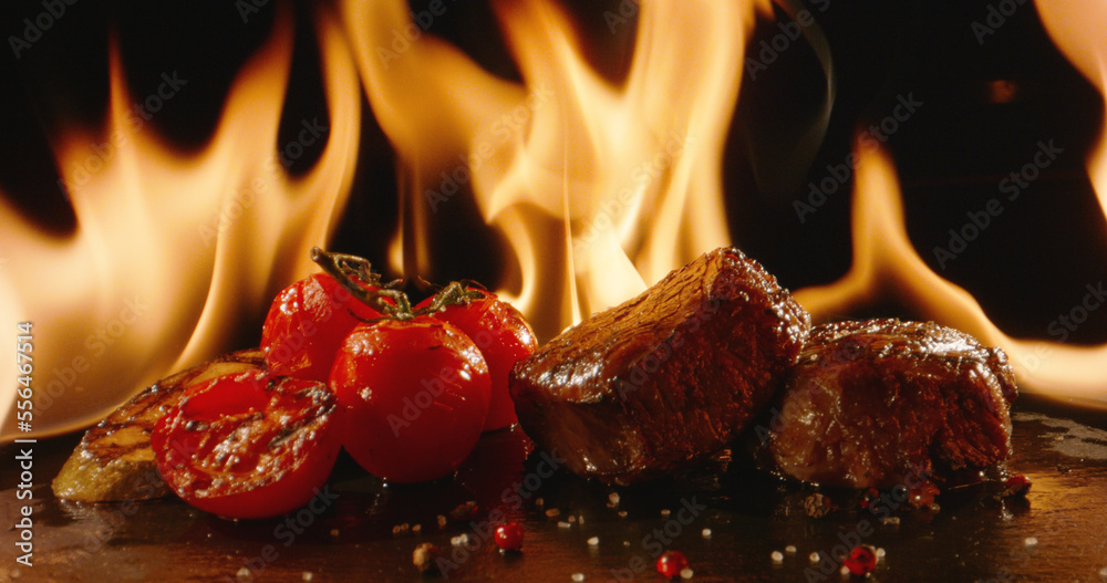 Epic shot of grilled meat fillet with vegetables in fire on grill. Meat being cooked in oven, set in