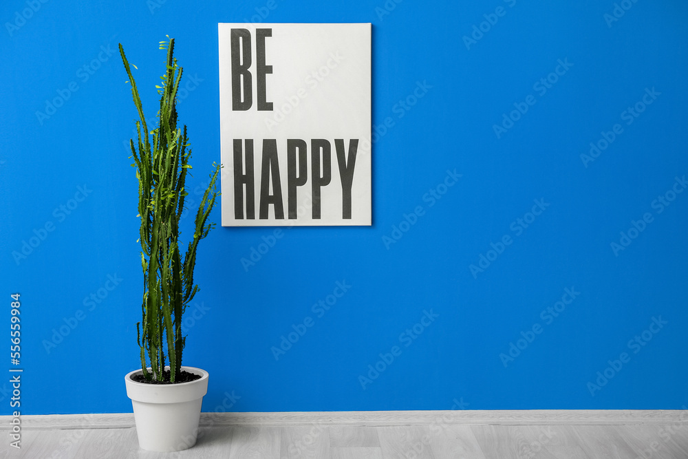 Green cactus and poster near blue wall in room