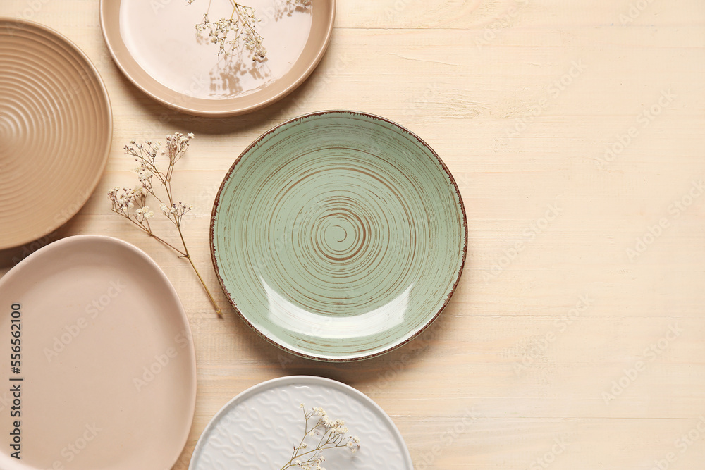 Empty plates and floral decor on beige background