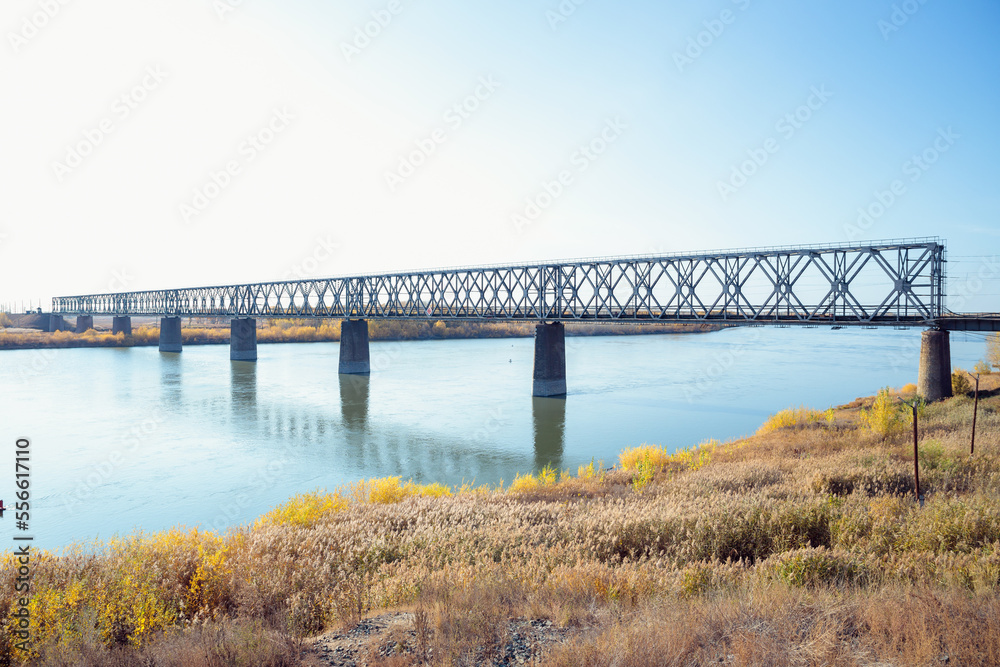 Railway bridge over river on sunny autumn day.