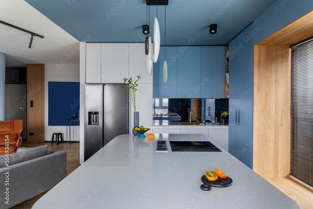 Creative composition of kitchen interior with marble kitchen island, blue kitchen furnitures, gray f