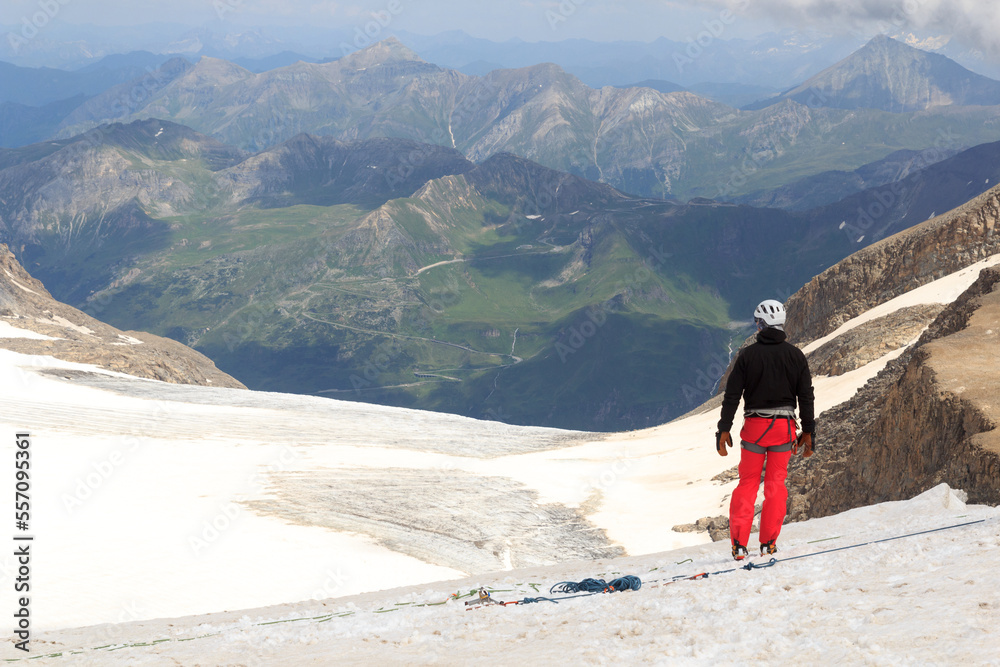 Mountaineer standing on glacier and looking towards Grossglockner High Alpine Road and mountain pano