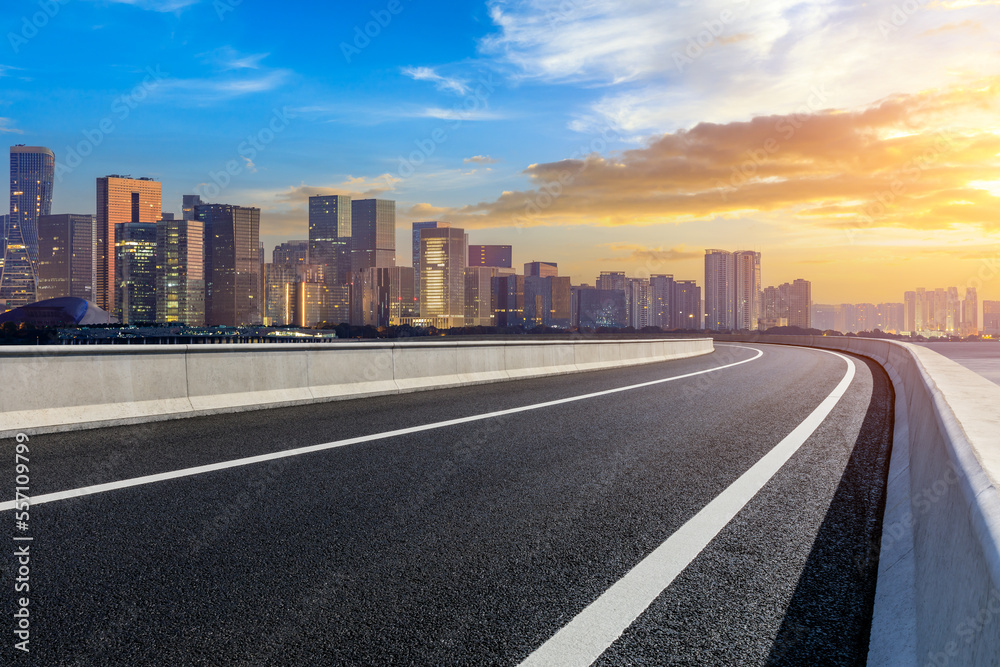 Empty asphalt road and modern city skyline with buildings in Hangzhou at sunset, China.