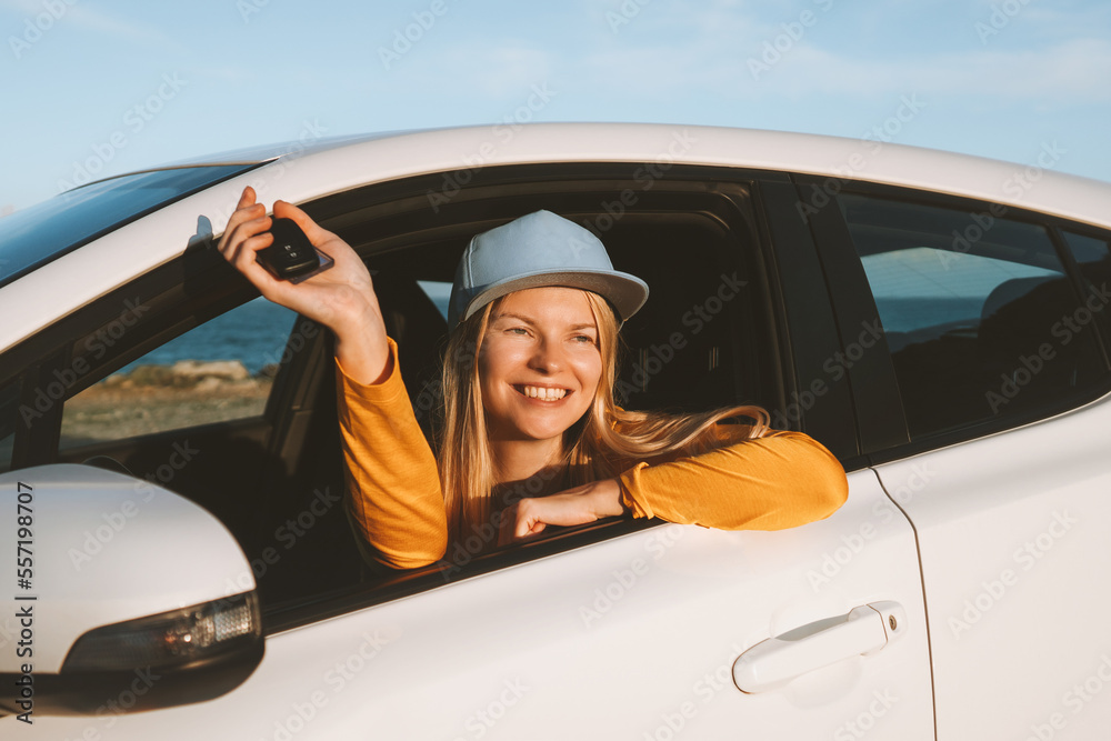 Woman driver traveling in a car showing keys open window. Road trip with rental automobile vacations