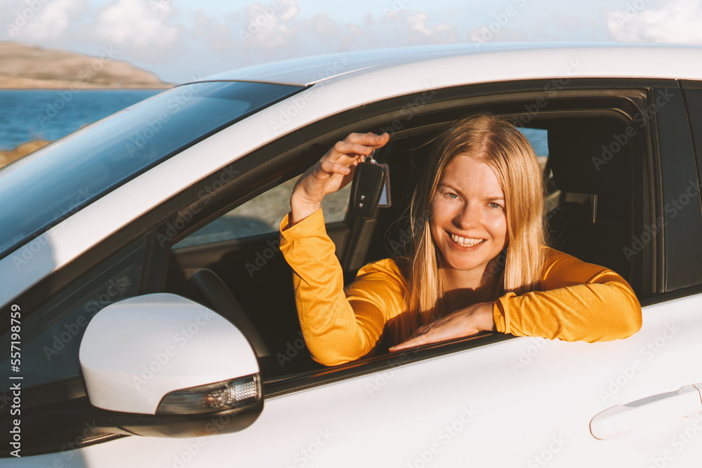 Woman driver in a car showing keys. Rental auto road trip vacations transport insurance concept elec