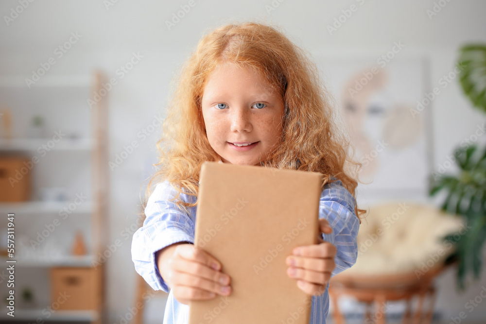 Little redhead girl with old book at home