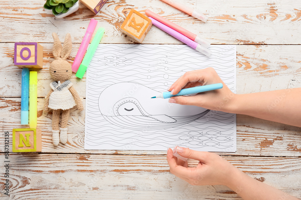 Woman coloring page with felt-tip pen on wooden background