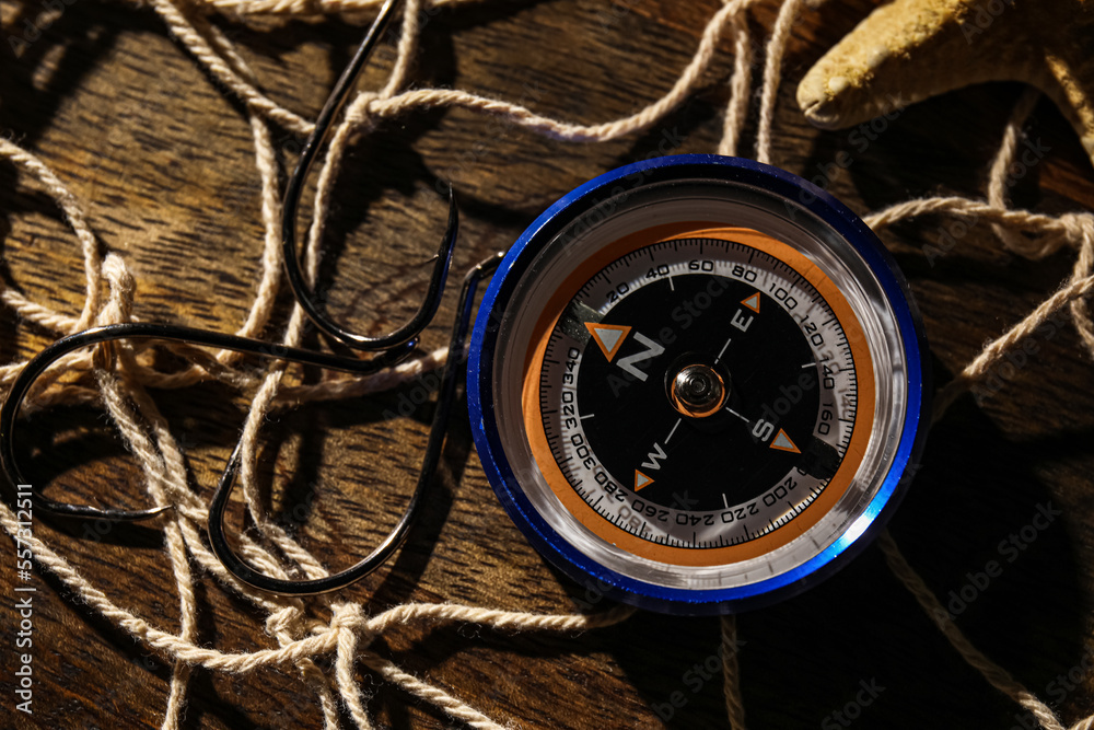 Compass with hooks and net on dark wooden background