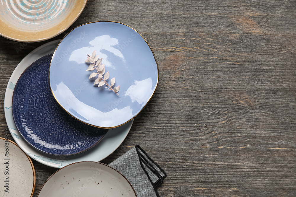 Different plates and floral decor on wooden background