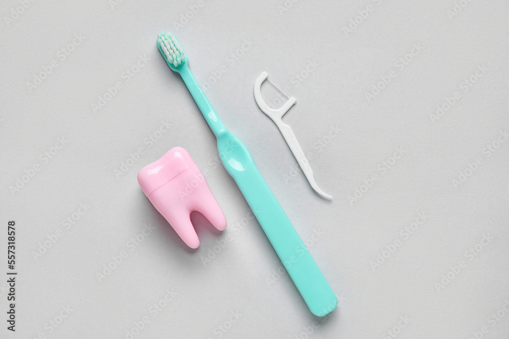 Plastic tooth, brush and toothpick on grey background