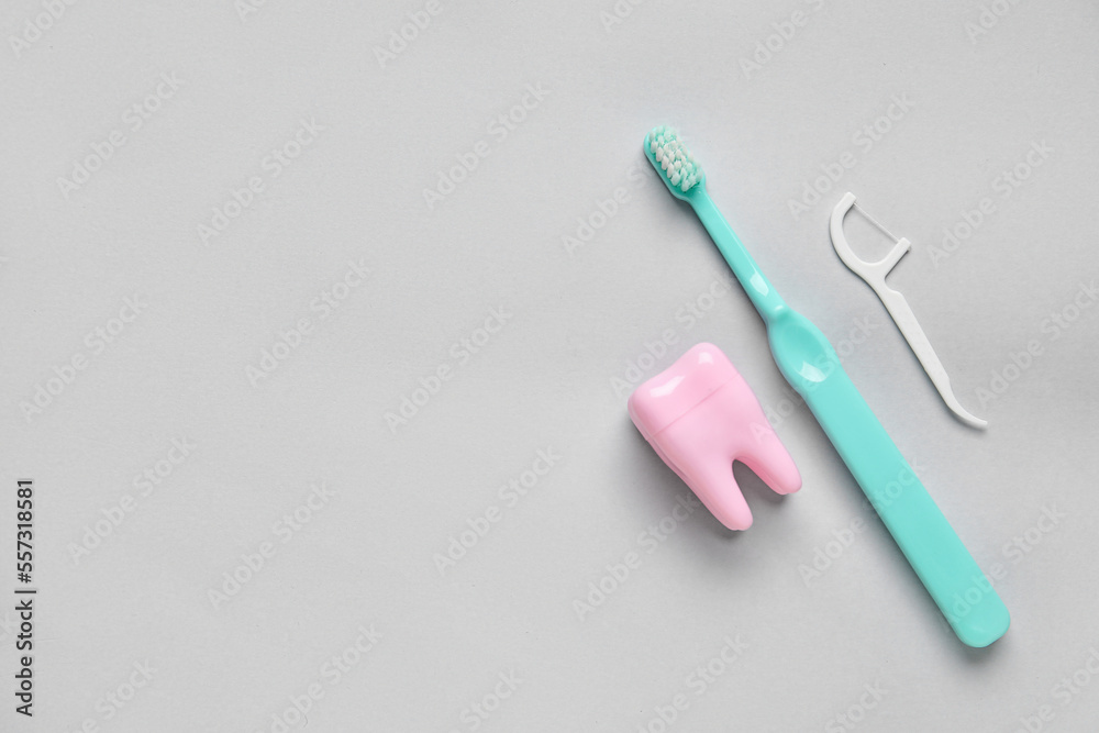 Plastic tooth, brush and toothpick on grey background