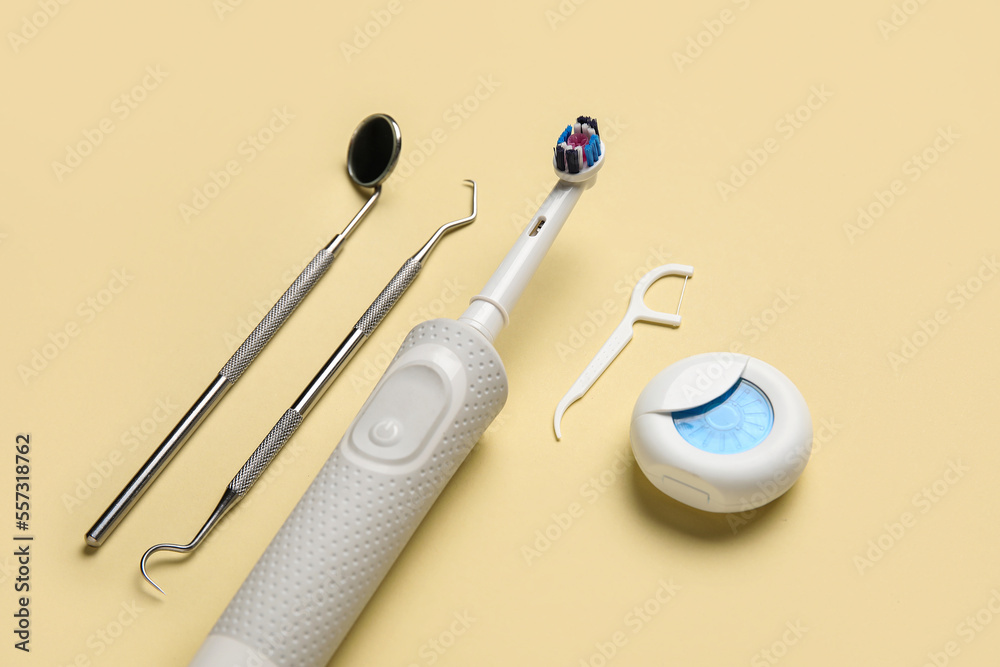 Dental tools with electric brush, toothpick and floss on yellow background