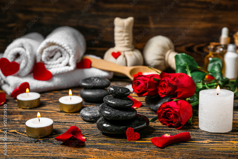 Spa stones with candles and roses on dark wooden table, closeup. Valentines Day celebration