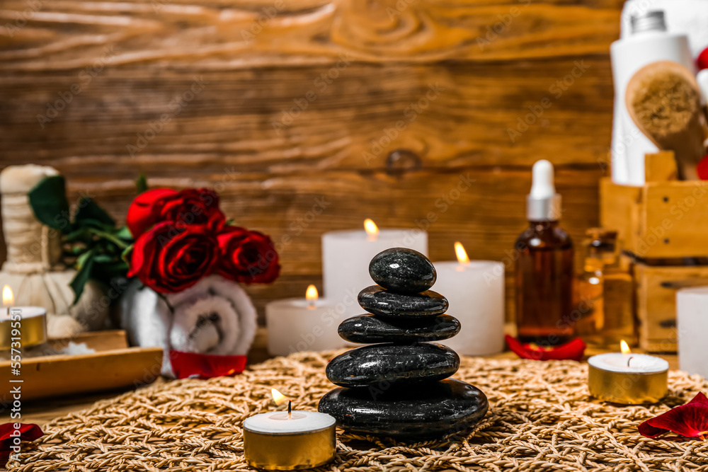 Spa stones with burning candle on wooden table, closeup. Valentines Day celebration