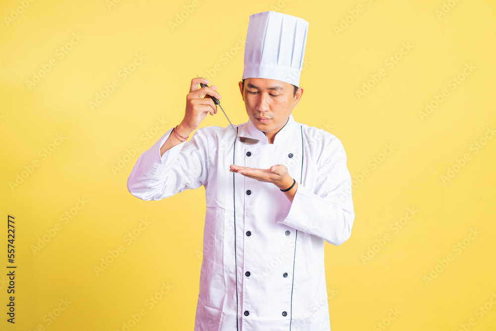 Asian male chef tasting hot food with a ladle on isolated background