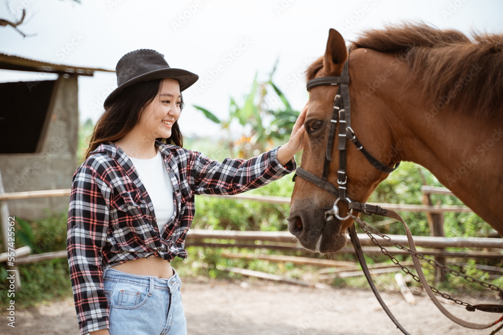 戴牛仔帽的女人在牧场抚摸马头