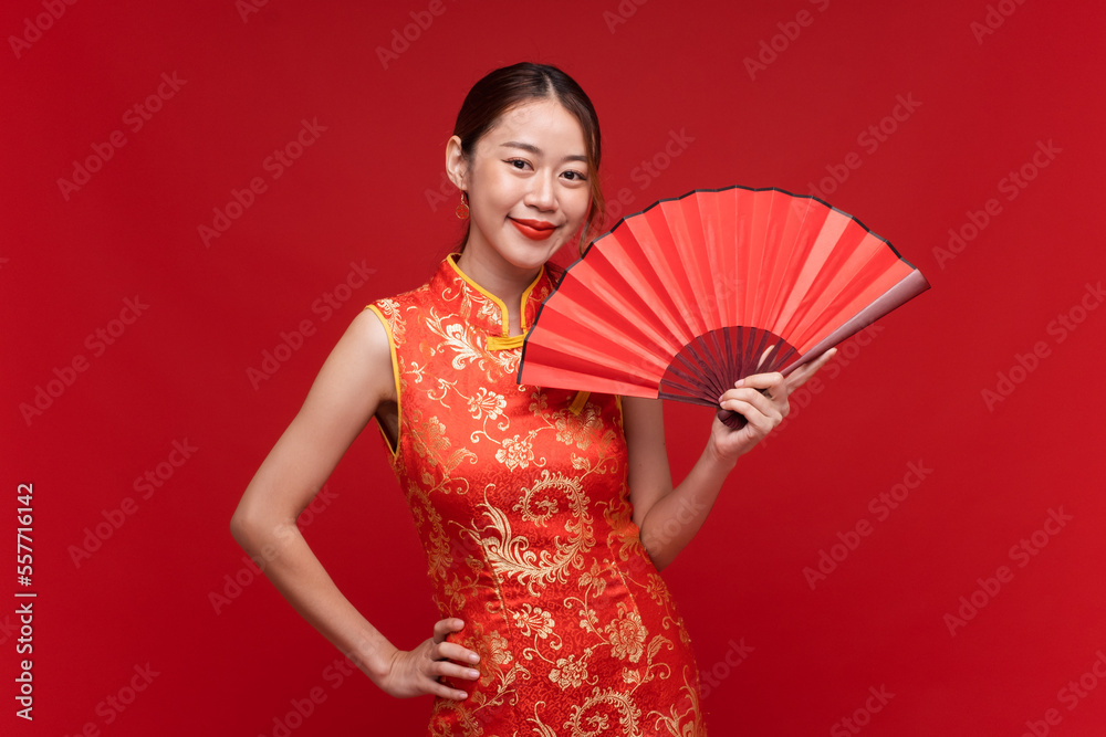 年轻的亚洲女性，身穿中国红底折扇的qipao-cheungsam连衣裙