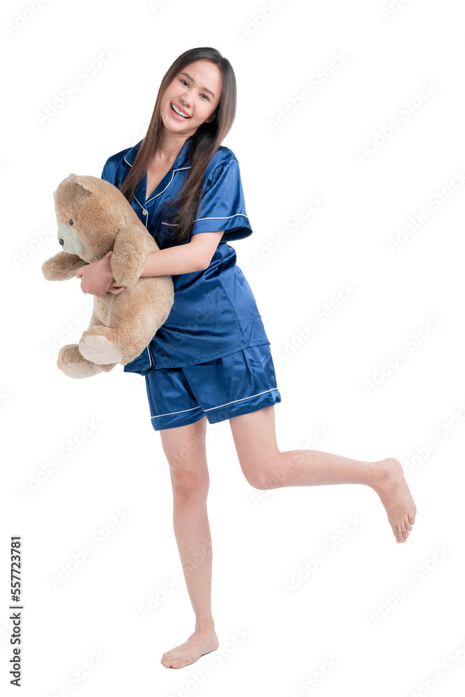 Young asian teen woman with cosy sleep wear hugging teddy bear stuffed animal with happy face smilin