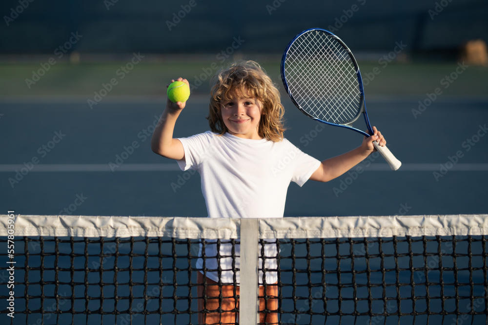 Child playing tennis on outdoor court. Kid with tennis racket and tennis ball playing on tennis cour