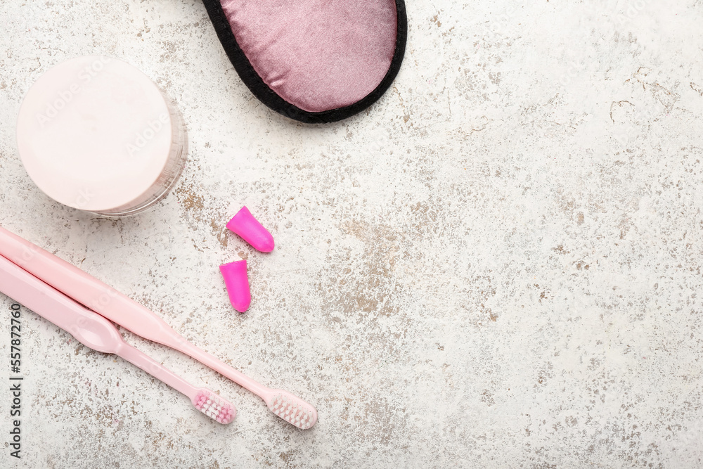 Earplugs, toothbrushes and jar of cream on light background