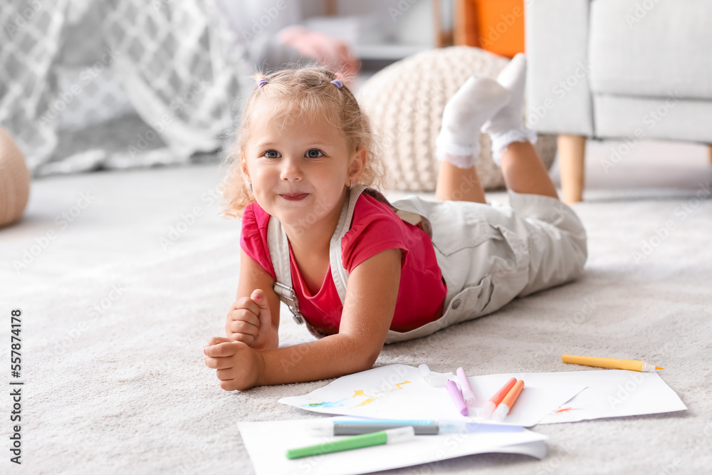 Cute little girl drawing with felt-tip pens on floor at home