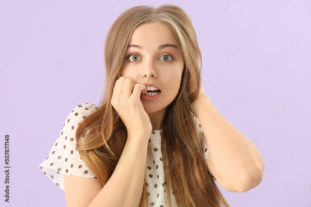 Young woman biting nails on lilac background, closeup