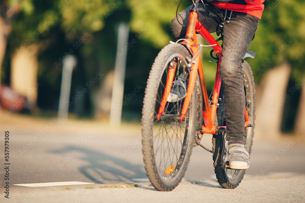 Boy riding a bike on the sidewalk along asphalt road.