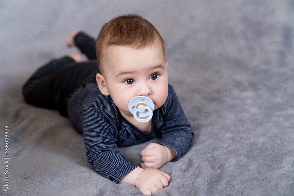 Cute baby with a pacifier. Cute infant boy about relaxing at home. Toddler baby boy playing with dum