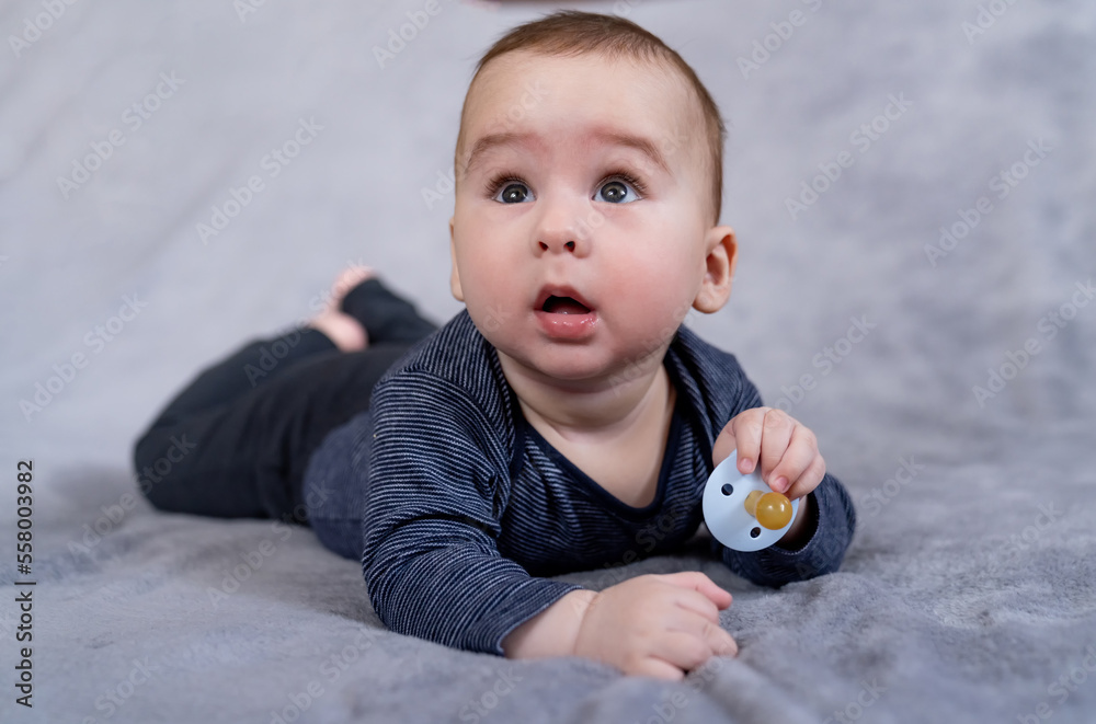 Cute baby with a pacifier. Cute infant boy about relaxing at home. Toddler baby boy playing with dum