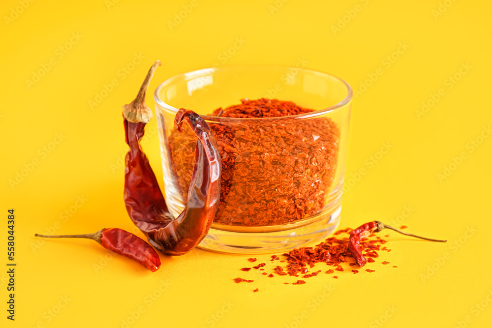 Bowl of chipotle chili flakes on color background