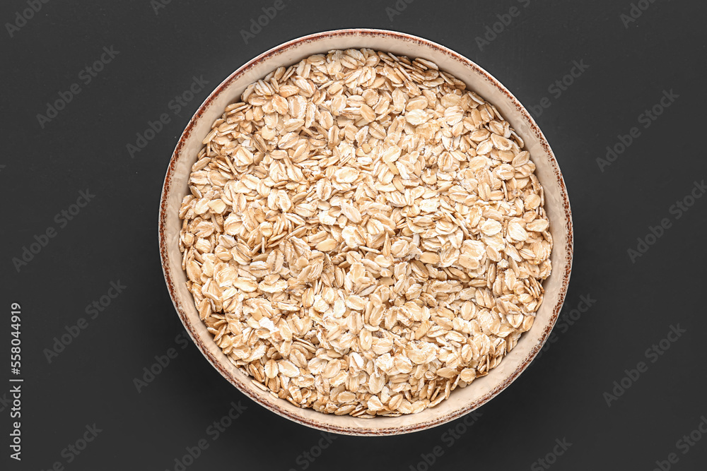 Bowl of raw oatmeal on dark background