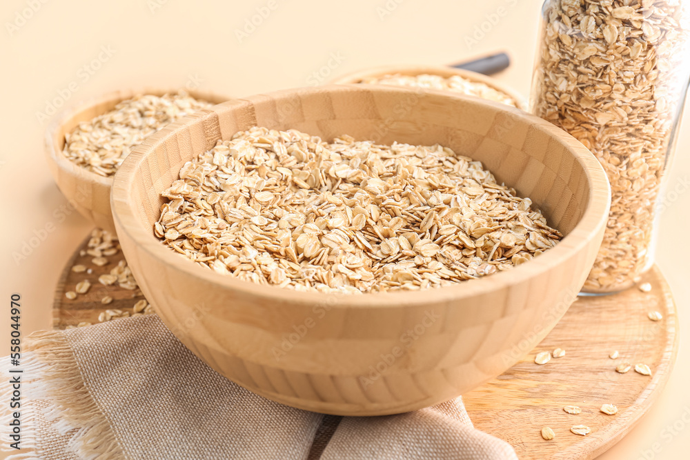 Wooden bowl with raw oatmeal on background, closeup