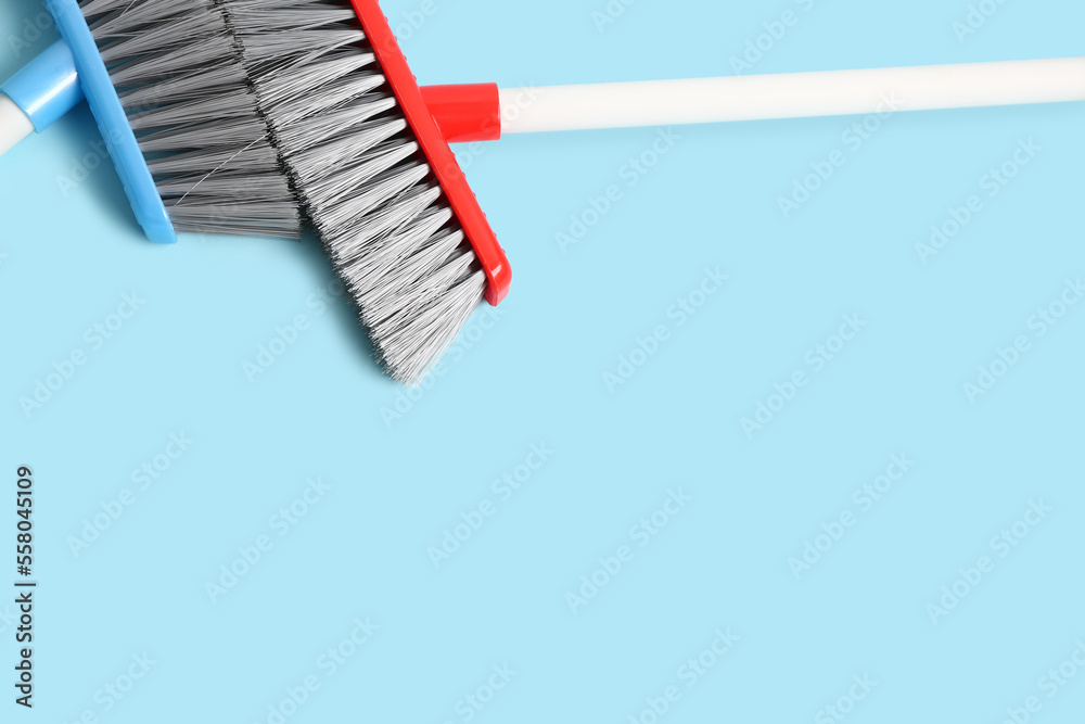 Cleaning brooms on color background