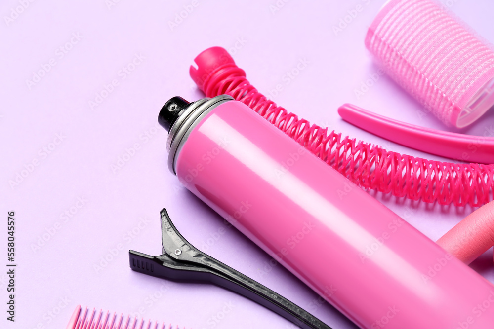 Hair spray with curlers and clips on lilac background, closeup