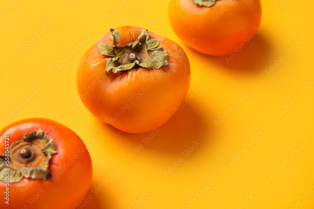 Fresh ripe persimmons on color background, closeup