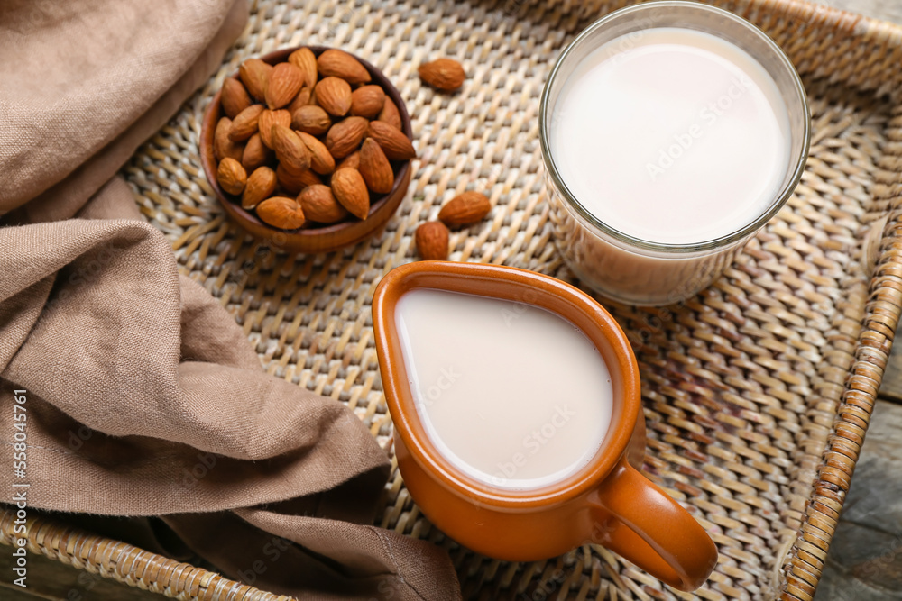 Tray with jug, glass of almond milk and nuts, closeup