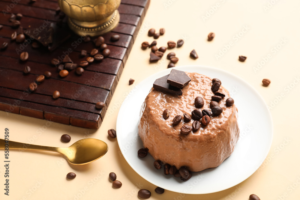 Plate with delicious pudding, coffee beans, chocolate and board on beige background