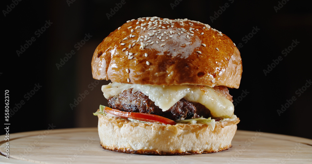 Amazing tasty appetizing burger with various fresh ingredients and buns on wooden board, isolated on