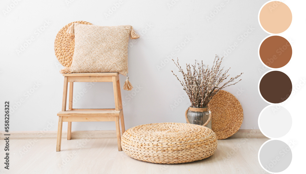 Vase with willow branches, rattan pouf and stepladder with pillow near light wall. Different color p